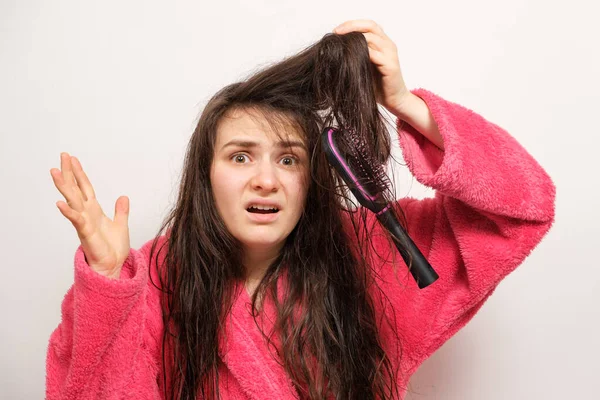 Una mujer con el pelo enredado largo húmedo trata de peinar — Foto de Stock