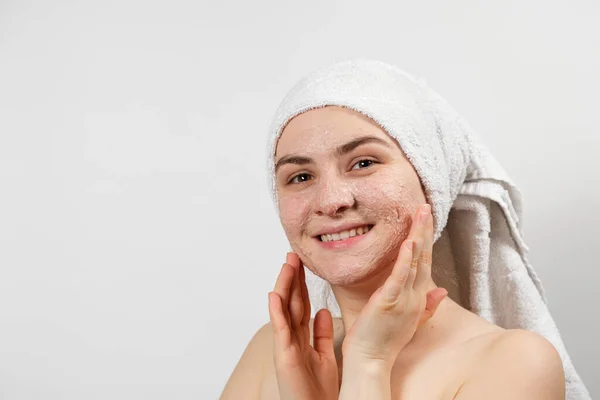Une belle jeune femme a appliqué un gommage ou un masque sur son visage, soin du visage, nettoyage de la peau — Photo