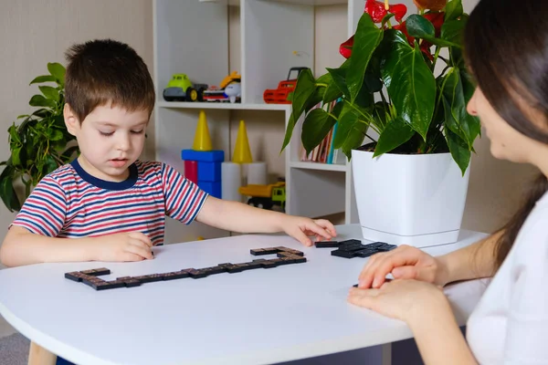Mam en zoon spelen domino. Bordspellen voor kleuters. — Stockfoto
