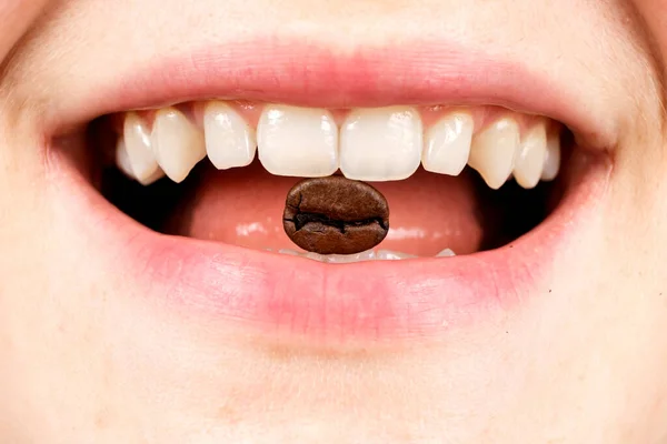 Grão de café em uma boca de mulher, close-up da boca. Vício em café, cafeína — Fotografia de Stock