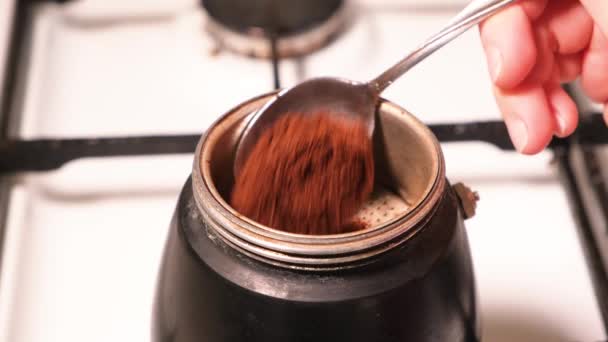 Proces nalewania świeżej kawy mielonej do ekspresu do kawy gejzera stojącego na piecu gazowym — Wideo stockowe