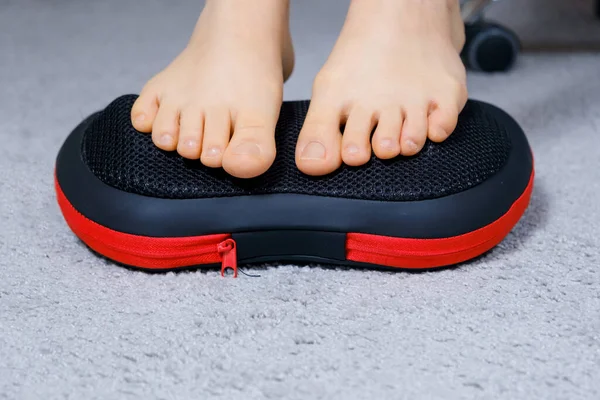 Womens feet on a massage pillow, relieving leg fatigue after a days work. — Stock Photo, Image