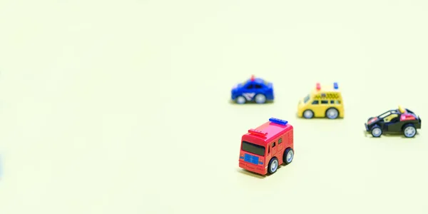 Hračky plastové autíčka na světle nažloutlém pozadí s místem pro text. Hračky pro děti, banner pro hračkářství. — Stock fotografie