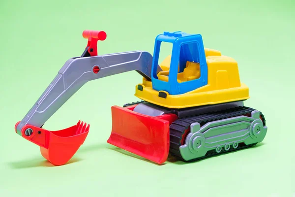 Excavator galben masina de plastic pe fundal verde. Mașini de construcții mașină pentru săpat pentru magazin de jucării și copii. — Fotografie, imagine de stoc