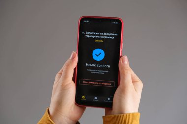 21 Mart 2022, Zaporozhye, Ukrayna. Hava saldırısı alarmı uygulaması aktif olan birinin elinde bir akıllı telefon var. Ukraynaca çeviri - Alarm yok