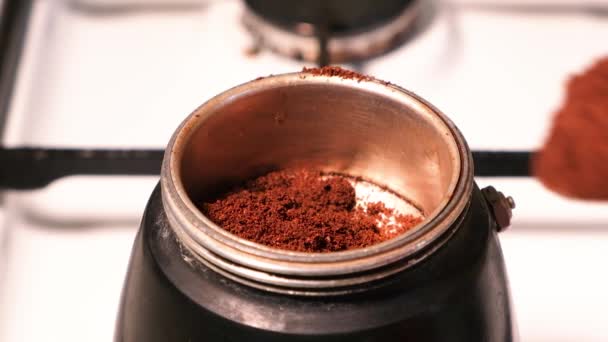 Процесс заливки молотого свежего кофе в гейзер кофеварка стоя на газовой плите — стоковое видео