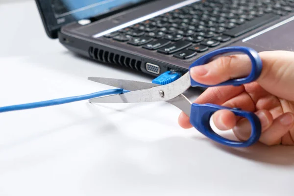 Scissors cut the Internet cable connected to the laptop. Turning off the internet, wi-fi — Stock Photo, Image