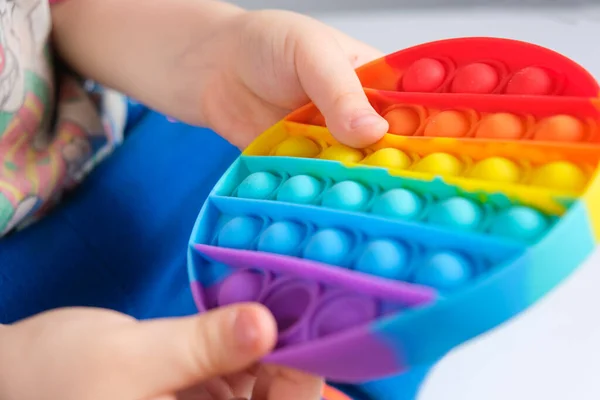 Un niño juega con pop it, los niños manos de cerca presionan las espinillas de los juguetes anti-estrés. — Foto de Stock