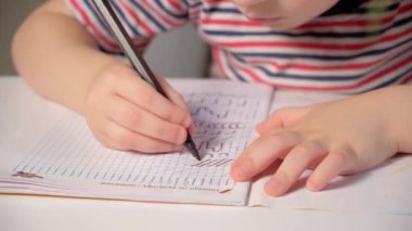 Anaokulu çocuğu yazmayı, defter yazmayı ve elleri yakın plan çekmeyi öğreniyor..