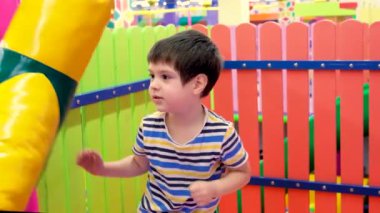 4 yaşında bir anaokulu çocuğu, oyun odasında boks yapmak için kum torbasıyla, çocuklar için de eğlence merkezi ile oynuyor.