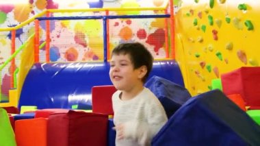 Güzel anaokulu çocuğu büyük yumuşak küplerle havuzda oynuyor, küp atıyor ve oyun odasında eğleniyor..