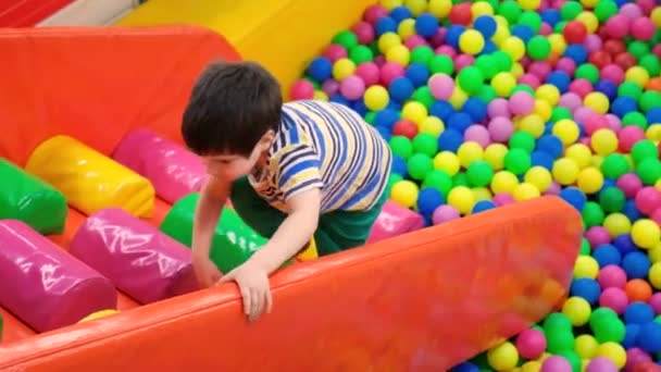 少年は柔らかいボールでプールから色の柔らかい階段でスライドを登り 子供のための遊び場 — ストック動画