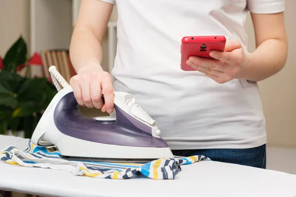 Een Vrouw Staat Naast Een Strijkplank Met Een Strijkijzer Kijkt — Stockfoto