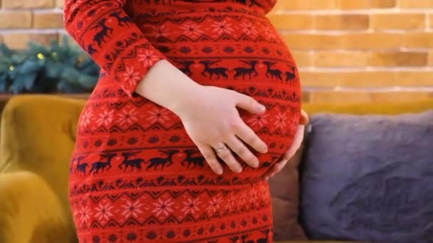 Mujer embarazada feliz en vestido rojo de invierno bailando y divirtiéndose, preparándose para la Navidad, primer plano vientre. — Vídeos de Stock