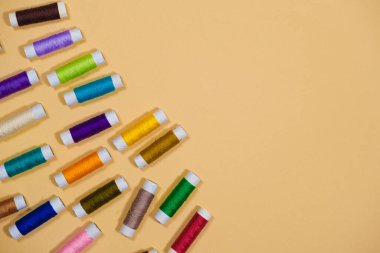 Bej bir arkaplan, üst görünüm üzerinde metin için boş bir boşluk ile dikmek için çok renkli iplikler seti. Terzilik ve dikiş malzemeleri, terzi afişi