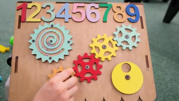Πολυάσχολος πίνακας για παιδιά, ξύλινος πίνακας με αριθμούς, γρανάζια περιστρέφονται. Αίθουσα παιχνιδιών και η ανάπτυξη των λεπτών κινητικών δεξιοτήτων και την προσοχή. — Αρχείο Βίντεο
