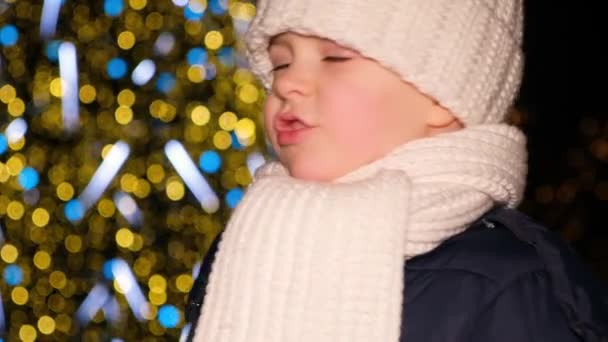 Ευτυχισμένο 4χρονο αγόρι γελάει και διασκεδάζει έξω από το χριστουγεννιάτικο δέντρο το χειμώνα, σε αργή κίνηση. — Αρχείο Βίντεο