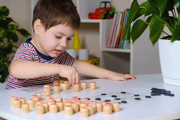 Un niño de 4 años juega loto, estudia números usando un juego de mesa. — Foto de Stock