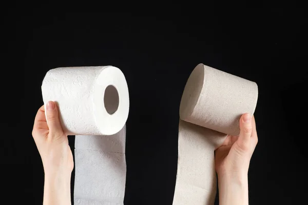 Bir insanın elinde iki çeşit tuvalet kağıdı vardır. Beyaz, yumuşak kâğıt ve siyah arka plandaki atık kağıttan gri. — Stok fotoğraf