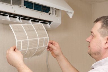 Usta klimanın tozlu filtresini kaldırıyor. Klimaların bakımı ve onarımı.