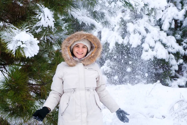 A woman in a winter snowy forest smiles looking at the camera, snowflakes fly by. — стоковое фото