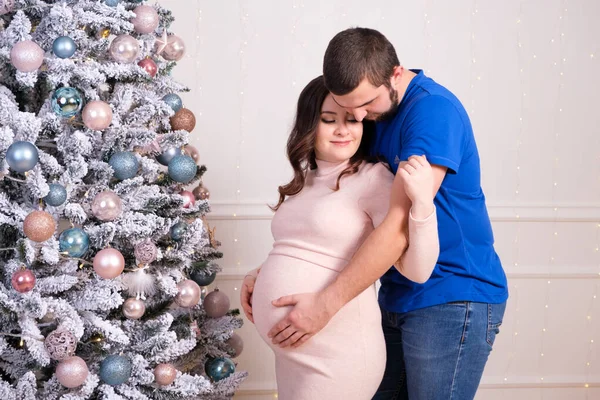 Mari et femme profitent de la grossesse ensemble, debout près du sapin de Noël. Joyeux bébé attendre et Noël — Photo