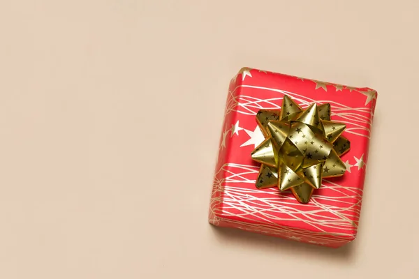 Piros ajándék doboz vonalak és csillagok egy nagy arany íj egy bézs háttér, hely a szöveg — Stock Fotó