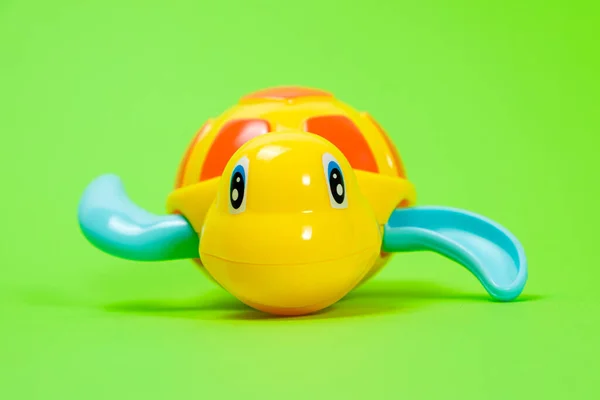 Yellow plastic turtle for playing in the water on a green background. Toys for babies for bathing — Fotografia de Stock