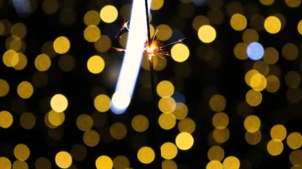 Λαμπερά σπινθηροβόλα πυρά στο φόντο του κίτρινου θολή bokeh του χριστουγεννιάτικου δέντρου. — Αρχείο Βίντεο
