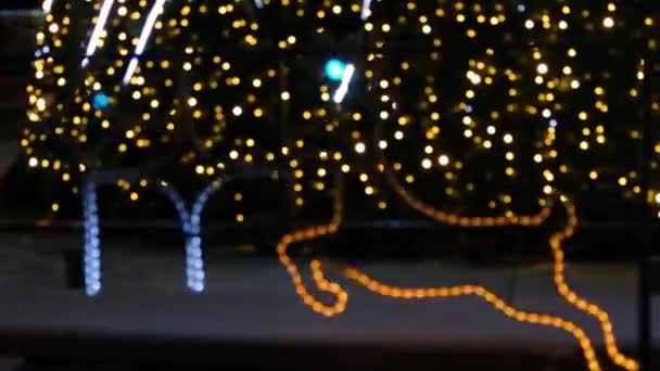 Leuchtende Lichterketten in Form von Sternen und Hirschen in der Nähe des Weihnachtsbaums. Dekorationen für das neue Jahr. — Stockvideo