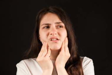 A woman holds her hands to a sore temporomandibular joint, dysfunction and pain, dislocated jaw, problems of wisdom teeth. clipart