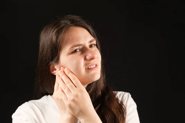 A woman holds her hands to a sore temporomandibular joint, dysfunction and pain, dislocated jaw, problems of wisdom teeth. — Stock Photo, Image