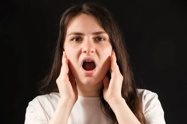 Μια γυναίκα με ανοιχτό στόμα κρατά τα μάγουλά της με τα χέρια της, ασκήσεις για τη δυσλειτουργία της κροταφογναθικής άρθρωσης — Φωτογραφία Αρχείου