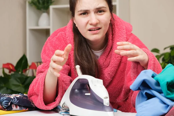 Yorgun eş bir ütüyle elbiselerini ütüleyecek. Ev ödevinden dolayı yorgunluk.