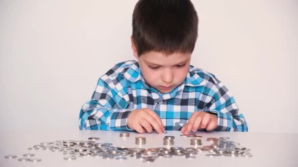 一个穿着格子呢衬衫的学龄前男孩数着硬币，建造着塔楼。儿童金融知识普及. — 图库视频影像