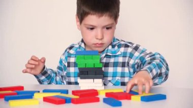 A preschool boy plays table jenga, carefully builds a tower of colorful wooden blocks. May 9, 2022, Zaporozhye, Ukraine