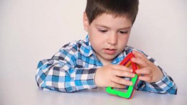 A boy of 4 years plays with a magnetic constructor, gets angry, knocks his hands and details on the table, throws toys