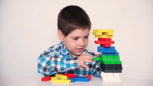 4 세 소년 이 다양 한 색상의 블록을 타워에서 끌어내는젠가의 보드게임을 한다. 사려깊음 과 균형을 주는 놀이 — 비디오