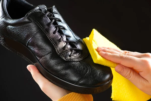 A man wipes leather mens black shoes with a yellow shoe rag. Cleaning from dust, shoe care