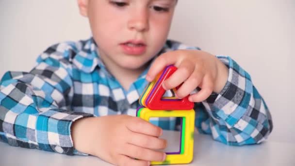 Un niño de 4 años juega con un constructor magnético, primer plano de sus manos. Desarrollo del pensamiento, juguetes creativos para niños. — Vídeos de Stock