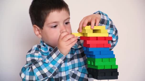 Seorang anak berusia 4 tahun memainkan permainan papan jenga, menarik blok berwarna-warni keluar dari menara. Permainan kesadaran dan keseimbangan. 9 Mei 2022, Zaporozhye, Ukraina — Stok Video