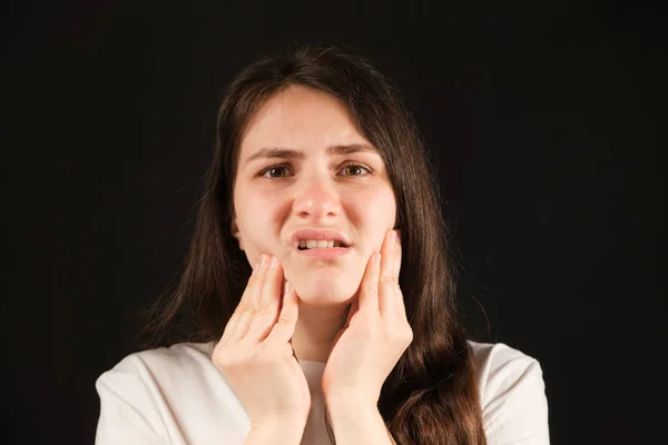 Uma mulher segura as mãos a uma articulação temporomandibular dolorida, disfunção e dor, mandíbula deslocada, problemas de dentes sabedoria. — Fotografia de Stock