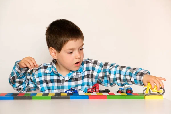 4岁的学龄前男孩玩汽车和玩具，玩儿童游戏，开白色背景的玩具店. — 图库照片