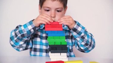 A preschool boy plays table jenga, carefully builds a tower of colorful wooden blocks. May 9, 2022, Zaporozhye, Ukraine
