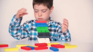 Anaokulundan bir çocuk çok renkli tahta bloklarla oynar, bir kule inşa eder.