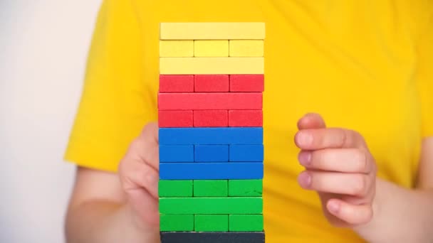 A woman in a yellow T-shirt plays a board game of jenga, gently pulls the rhizome blocks out of the tower. 14 May 2022, Zaporozhye, Ukraine. — Stock video