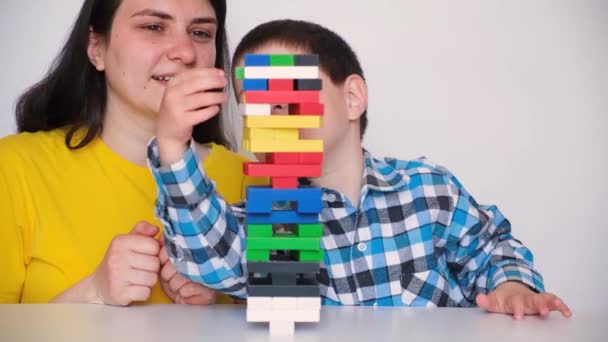 Anya és fia társasjátékot játszanak Jenga, óvatosan húzza színes blokkok a toronyból. 2022. május 14., Zaporozhye, Ukrajna. — Stock videók