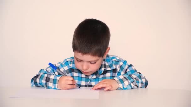 A 4-year-old boy draws circles on paper with a blue marker. Childrens drawing. — Vídeo de Stock