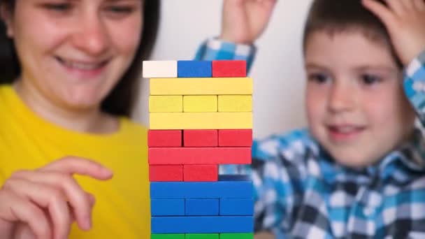 Mother and son play a board game, carefully pulling colorful blocks from the tower. — Αρχείο Βίντεο