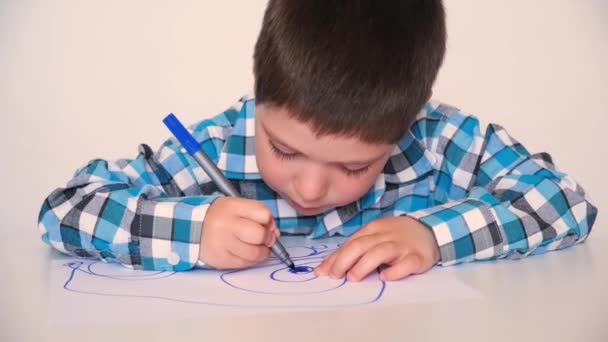 A 4-year-old boy draws circles on paper with a blue marker. Childrens drawing. — Vídeo de Stock